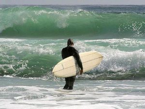 Surfer debout avec sa planche sous le bras dans l'ocean